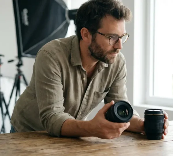 Photographe examinant plusieurs objectifs photo posés sur une table en studio